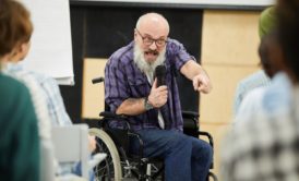 man in wheelchair presenting to a crowd