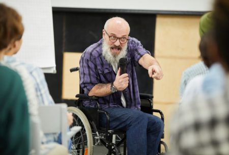 man in wheelchair presenting to a crowd