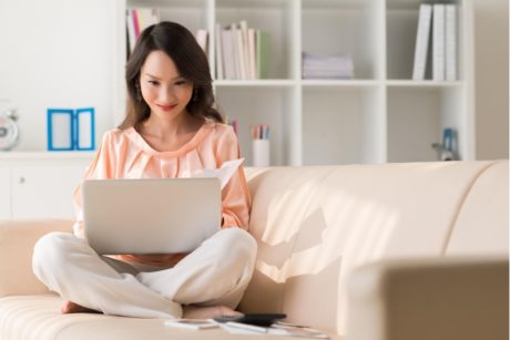 woman sitting on couch typing in laptop