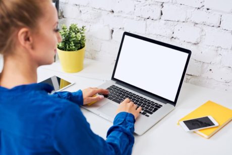 woman in blue shirt typing on laptop