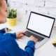 woman in blue shirt typing on laptop