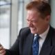 a businessman in suit checking phone, likely participating in online anger management course