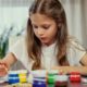 young girl happily painting with colorful acrylics on her hands at an acrylic painting workshop