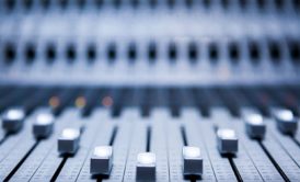 close-up of a mixing board with numerous knobs, used for composing ambient music in a creative studio setting