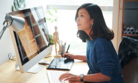 A woman at a desk, working on a computer and keyboard to create a WordPress website