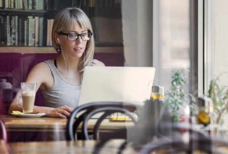 A woman in glasses working on a laptop at a table, focusing on freelance strategy consulting