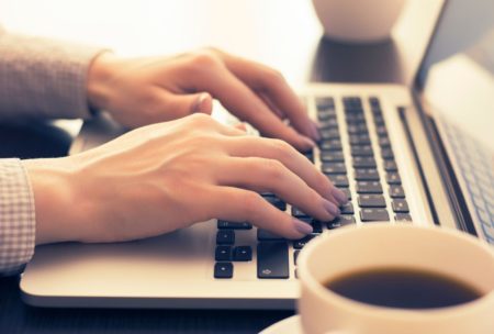 A person typing on a laptop computer, working on freelance remote jobs