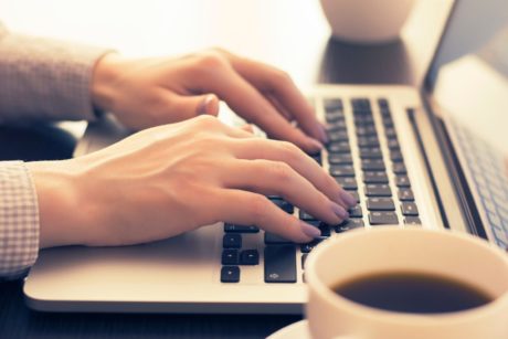 A person typing on a laptop computer, working on freelance remote jobs