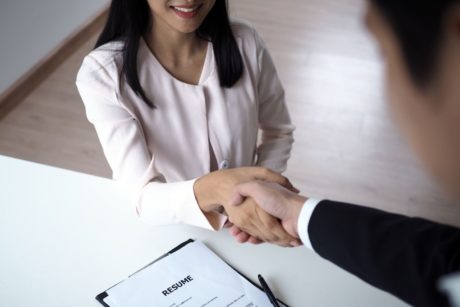 a woman and man shaking hands at a desk, symbolizing how to find your perfect job