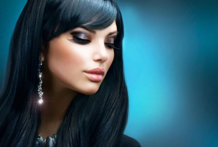 Elegant woman with long black hair and earrings, showcasing her stylish hair and make up