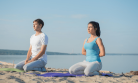 A serene couple practicing yoga on a sandy beach during a mindfulness meditation course