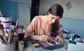 A woman focused on her artwork, painting in her studio while learning the art of painting for beginners