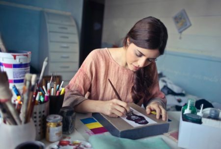 A woman focused on her artwork, painting in her studio while learning the art of painting for beginners