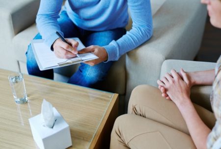 therapist in blue talking to patient