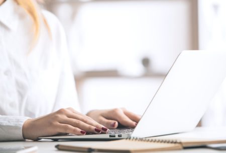 woman typing on white laptop