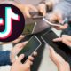 tiktok logo and group of people holding smartphones