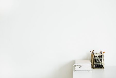 white desk with a notebook against a white wall