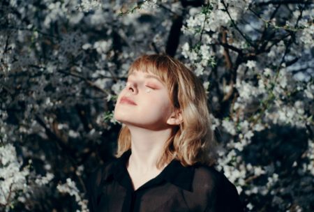 woman closing her eyes relaxing and staring at the sky