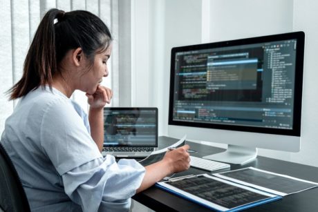 female javascript developer coding on white desktop computer