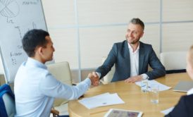 two men shaking hands in a corporate boardroom