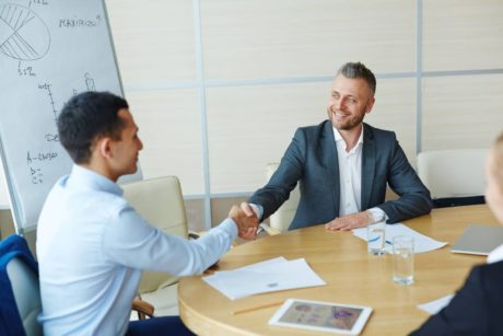 two men shaking hands in a corporate boardroom