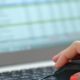 woman's hand with orange nail polish holding black computer mouse