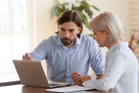 man in blue shirt mentoring an older woman with grey hair