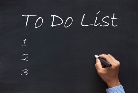 man writing to do list on chalkboard