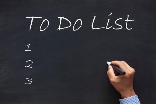 man writing to do list on chalkboard