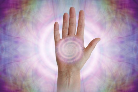 a hand displayed on a purple and pink background, with a central circle, illustrating the concept of chakra healing certification