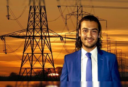 A professional man in a suit stands confidently before a row of electricity pylons, symbolizing an electrical design course