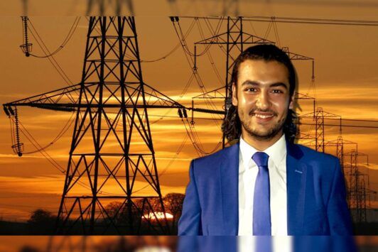 A professional man in a suit stands confidently before a row of electricity pylons, symbolizing an electrical design course