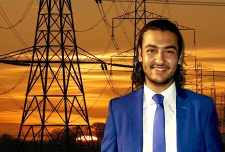 A man in a suit and tie stands before electricity pylons, conducting fault analysis.