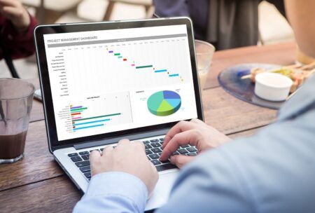 A person using a laptop with a chart on it. The image represents Microsoft Excel Beginner To Advanced.