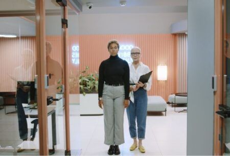 Two millennial women standing in front of a glass door, representing the onboarding process for young professionals