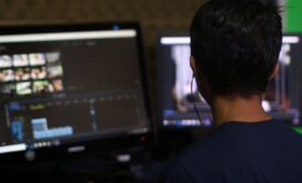 A young man focused on a computer screen, engaged in a tutorial on iMovie for Mac