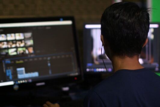 A young man focused on a computer screen, engaged in a tutorial on iMovie for Mac