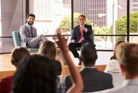 two business professionals seated, one gesturing with hand, discussing becoming a thought leader