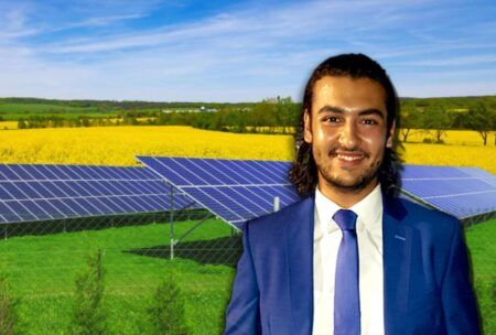 A man in a suit and tie standing in front of solar panels, showcasing solar energy design