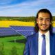 A man in a suit and tie standing in front of solar panels, showcasing solar energy design