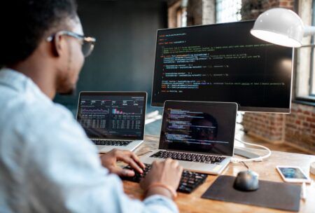 a man focused on his laptop and computer, working diligently. He is using chatgpt for programmer tasks