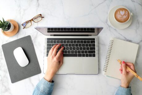 a woman's hands on a laptop keyboard on a marble table, discovering how to use google workspace