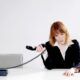 Image of a professional woman at a desk with a phone and a 10 minutes sign, handling abusive customers.