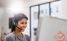 Woman wearing headset smiles at computer, delivering advanced customer service.