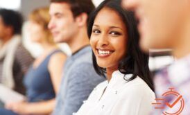 A woman smiling in front of a group of people, showing teamwork and unity.