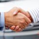 handshake between two people in front of a car, representing the secrets of closing the sale