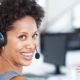 A woman with a headset, smiling brightly, showcasing excellent customer service skills and basic telephone techniques.