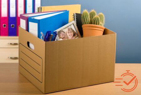 A desk showcases a box of books and pens, reflecting the process of coping with redundancy and seeking new opportunities.