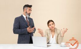 Two professionals in business clothes are seated at a table with a laptop, focused on a course about managing difficult customers.