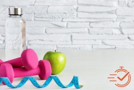 A bottle of water, a dumbbell, and an apple, showcasing key elements of health and wellness for a fit lifestyle.